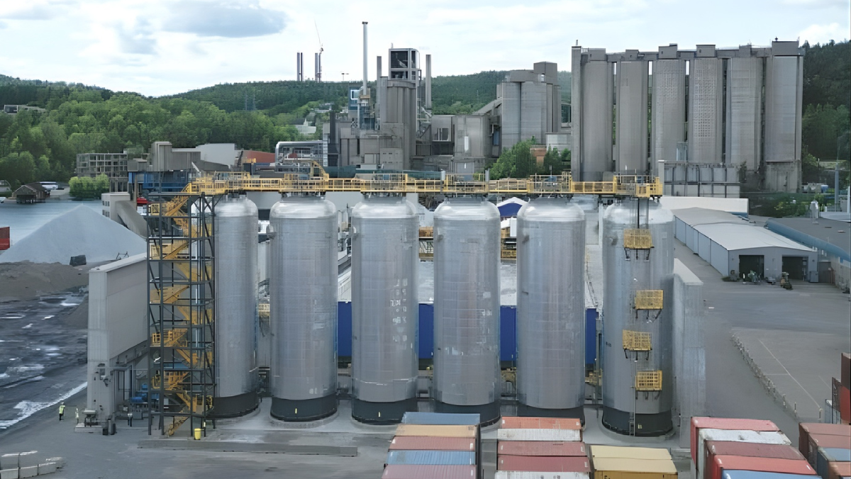 Industrial cement plant with large CO₂ capture tanks and storage infrastructure.